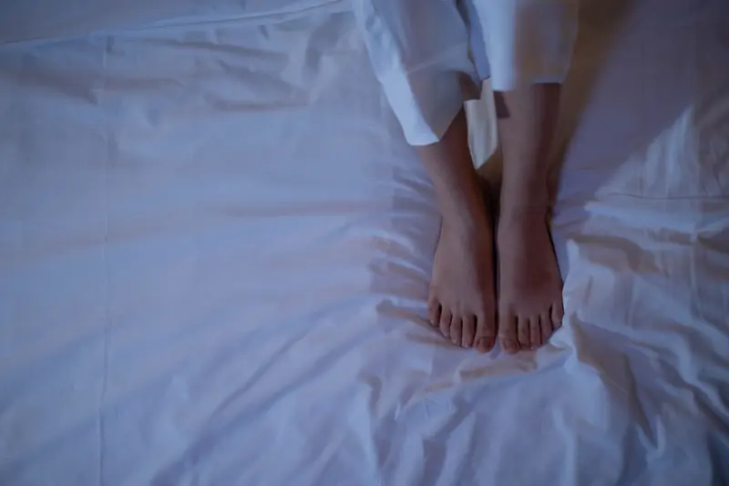 A pair of feet resting on white sheets, capturing a cozy and relaxed atmosphere from an overhead view